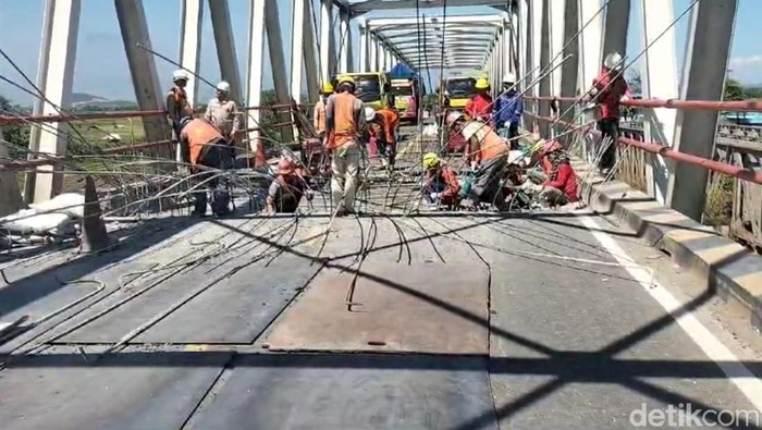 Pekerja memperbaiki jembatan Poncol Brebes yang rusak, Minggu (14/7/2024).