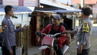 Anggota Polsek Suwawa berbincang dengan pengemudi ojek motor di jembatan gantung yang menjadi pintu masuk menuju tambang rakyat di Desa Tulabolo, Suwawa Timur, Kabupaten Bone Bolango, Gorontalo, Minggu (14/7/2024).