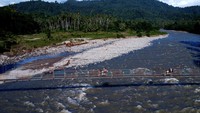 Warga melintasi jembatan gantung yang menjadi pintu masuk menuju tambang rakyat di Desa Tulabolo, Suwawa Timur, Kabupaten Bone Bolango, Gorontalo, Minggu (14/7/2024).