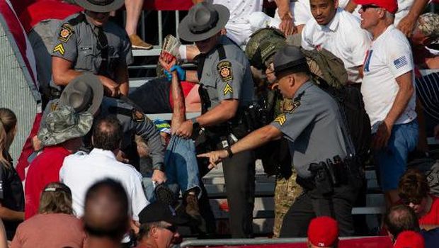 A person is removed by state police from the stands after guns were fired at Republican candidate Donald Trump at a campaign event at Butler Farm Show Inc. in Butler, Pennsylvania, July 13, 2024. The suspected shooter who wounded Republican presidential candidate Donald Trump at a rally is dead, US media reported Saturday, along with one bystander. (Photo by Rebecca DROKE / AFP)