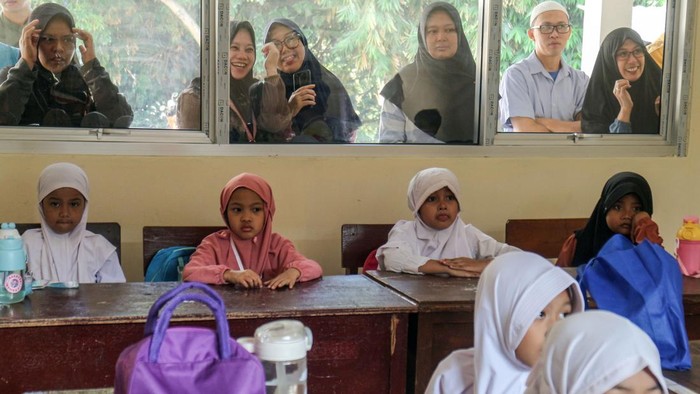 Sejumlah orang tua siswa memperhatikan anaknya yang mengikuti masa pengenalan lingkungan sekolah pada hari pertama masuk sekolah di Madrasah Ibtidaiyah Negeri 1, Kota Depok, Jawa Barat, Senin (15/7/2024). Hari pertama masuk sekolah tahun ajaran baru 2024-2025, diawali dengan masa orientasi guna memperkenalkan peserta didik kepada guru dan lingkungan sekolah. ANTARA FOTO/Yulius Satria Wijaya