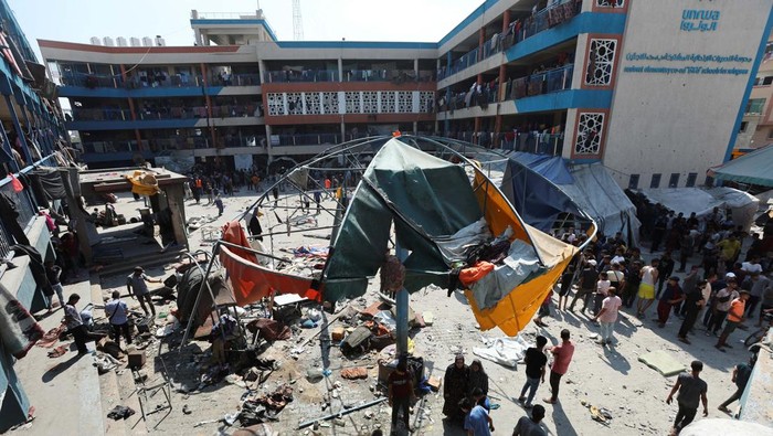 Kejam! Israel Kembali Serang Sekolah PBB Palestinians gather at the site of an Israeli air strike on a UN school sheltering displaced people, amid the Israel-Hamas conflict, in Nusairat in central Gaza Strip, July 14, 2024. REUTERS/Ramadan Abed