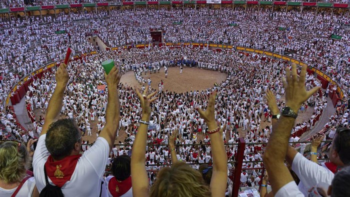 Attendees sing in the bullring during the final day of the San Fermin Festival in Pamplona, northern Spain, Sunday, July 14, 2024. Revellers from around the world flock to Pamplona every year for nine days of uninterrupted partying in Pamplona's famed running of the bulls festival. (AP Photo/Alvaro Barrientos)