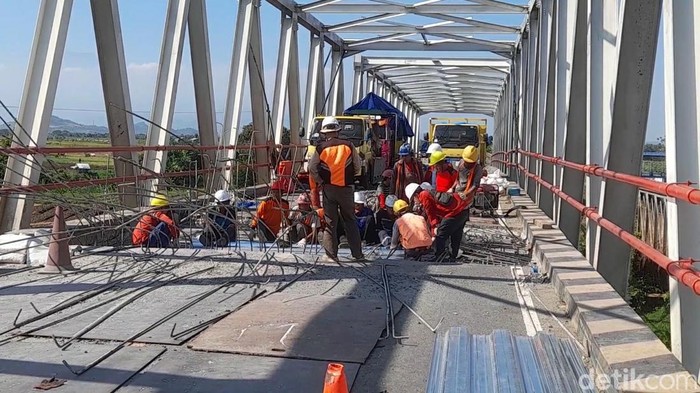 Pekerja memperbaiki jembatan Poncol Brebes yang rusak, Senin (15/7/2024).