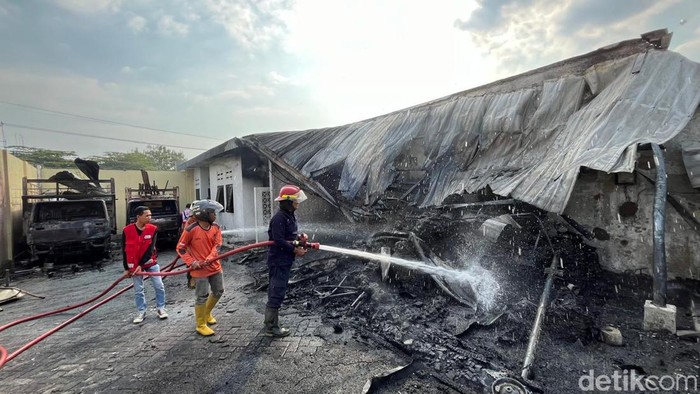Petugas lakukan pembasahan pabrik pengeringan plastik di Desa Mlaten, Puri, Mojokerto usai terbakar