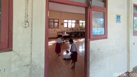 Dua orang siswi Kelas 2 SDN 1 Sentono sedang membersihkan kelas pada hari pertama masuk sekolah.