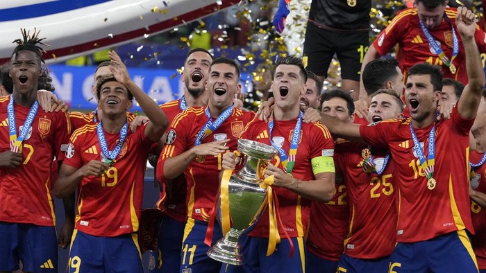 Spains Alvaro Morata holds the trophy as he celebrates with his teammates after winning the final match between Spain and England at the Euro 2024 soccer tournament in Berlin, Germany, Sunday, July 14, 2024. Spain won 2-1. (AP Photo/Frank Augstein)