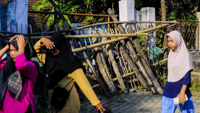 Sejumlah wali murid melintas di depan gerbang sekolah yang ditutup dengan tumpukan kayu di SD Negeri Kuranji, Kota Serang, Banten, Selasa (16/7/2024). Menurut pihak sekolah, akses gerbang utama sekolah tersebut sejak setahun terakhir ditutup oleh seseorang yang mengaku sebagai ahli waris sehingga para siswa yang akan masuk harus melalui jalan samping sekolah. ANTARA FOTO/Muhammad Bagus Khoirunas/tom.