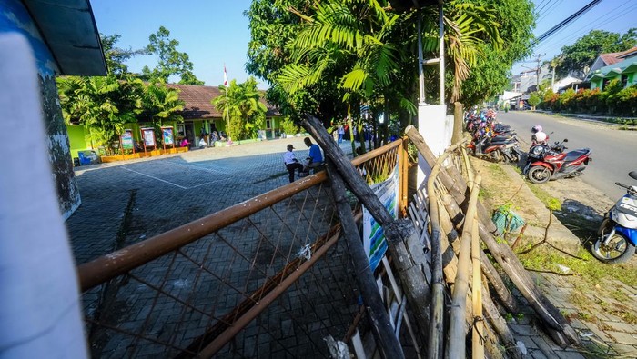 Sejumlah wali murid melintas di depan gerbang sekolah yang ditutup dengan tumpukan kayu di SD Negeri Kuranji, Kota Serang, Banten, Selasa (16/7/2024). Menurut pihak sekolah, akses gerbang utama sekolah tersebut sejak setahun terakhir ditutup oleh seseorang yang mengaku sebagai ahli waris sehingga para siswa yang akan masuk harus melalui jalan samping sekolah. ANTARA FOTO/Muhammad Bagus Khoirunas/tom.