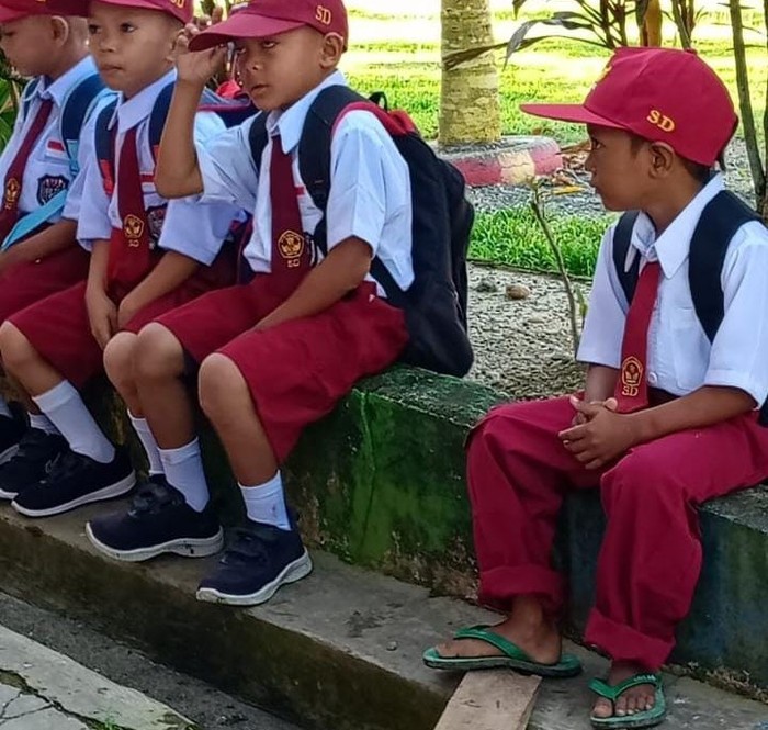 Muhammad Firdaus (kanan), siswa SD di Mamuju Tengah bersekolah menggunakan sendal jepit.