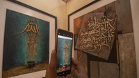 Pengunjung memotret lukisan dengan telepon pintarnya pada pameran lukisan kaligrafi di DPRD Kota Salatiga, Jawa Tengah, Selasa (16/7/2024).  