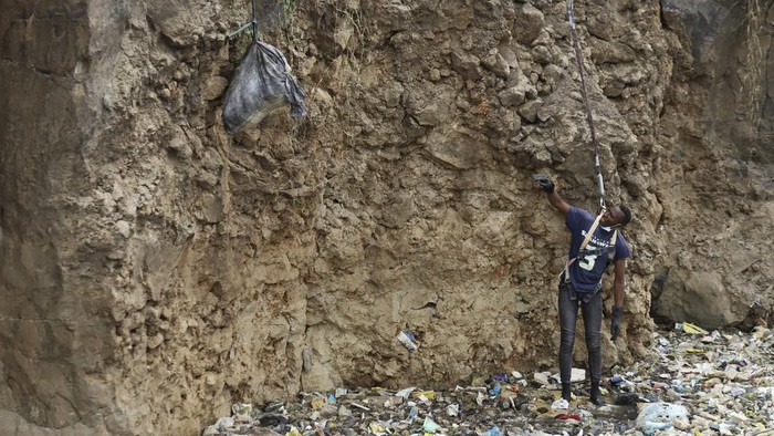 A man is lowered into a quarry where human remains were found in Mukuru kwa Njenga area, in Nairobi, Kenya Saturday, July 13, 2024. Police in Kenya said Monday they have arrested the main suspect after nine dismembered bodies of women were found in a quarry in the capital, Nairobi. (AP Photo/Andrew Kasuku)