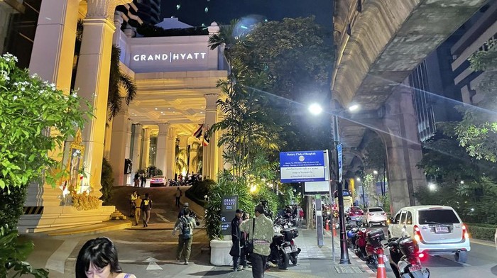 People walk outside a hotel where a number of people were found dead in Bangkok, Thailand, Tuesday, July 16, 2024. (AP Photo/Napat Kongsawad)