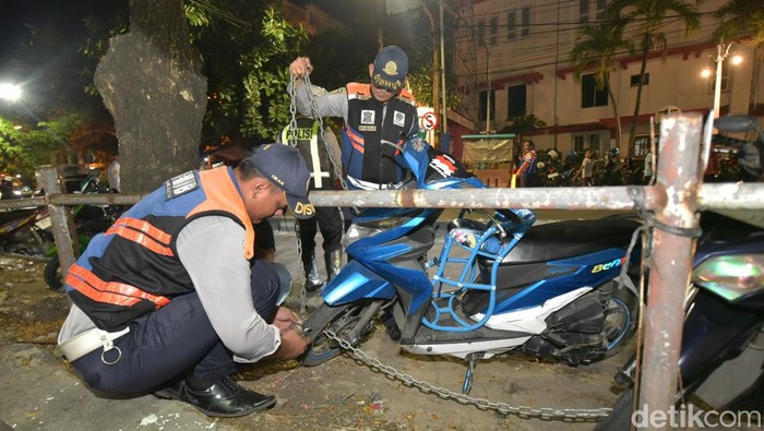 Petugas menggembok kendaraan yang parkir liar di Surabaya
