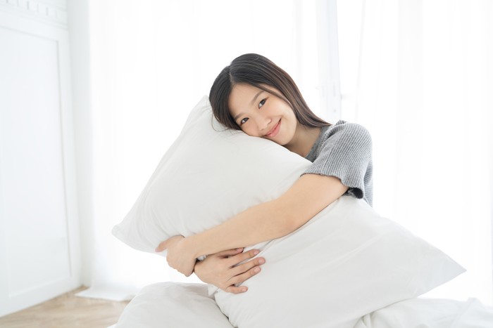 Portrait Asian woman and pillow wake up on bed at home