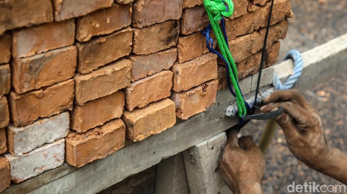 Buruh harian lepas menurunkan bata merah dalam proyek bangunan rumah di Jl Tambak, Jakarta Selatan, Kamis (17/7/2024). Para buruh ini mengaku dibayar Rp 85.000/hari. Jumlah tersebut terbilang pas-pasan untuk standar upah layak di Jakarta.
