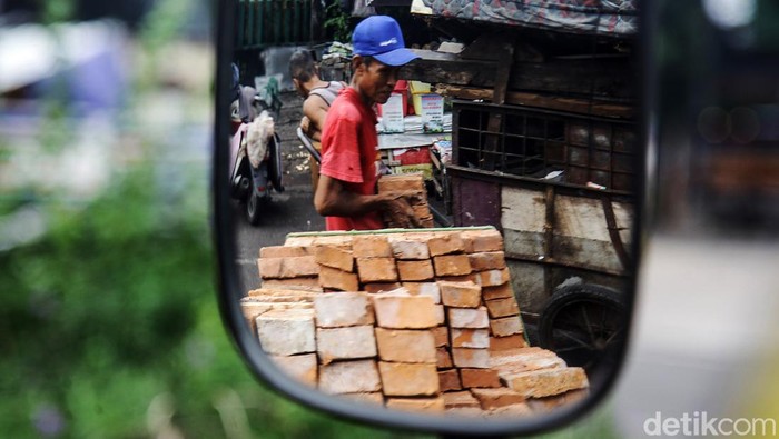 Buruh harian lepas menurunkan bata merah dalam proyek bangunan rumah di Jl Tambak, Jakarta Selatan, Kamis (17/7/2024). Para buruh ini mengaku dibayar Rp 85.000/hari. Jumlah tersebut terbilang pas-pasan untuk standar upah layak di Jakarta.