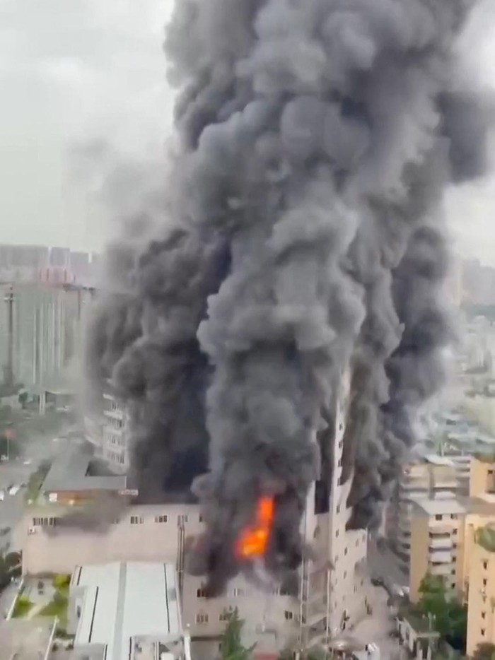 A person tries to climb outside a window during a deadly fire at a shopping centre, in the city of Zigong, Sichuan, China, July 17, 2024 in this screengrab taken from a social media video. Video Obtained By Reuters/via REUTERS  THIS IMAGE HAS BEEN SUPPLIED BY A THIRD PARTY. NO RESALES. NO ARCHIVES.