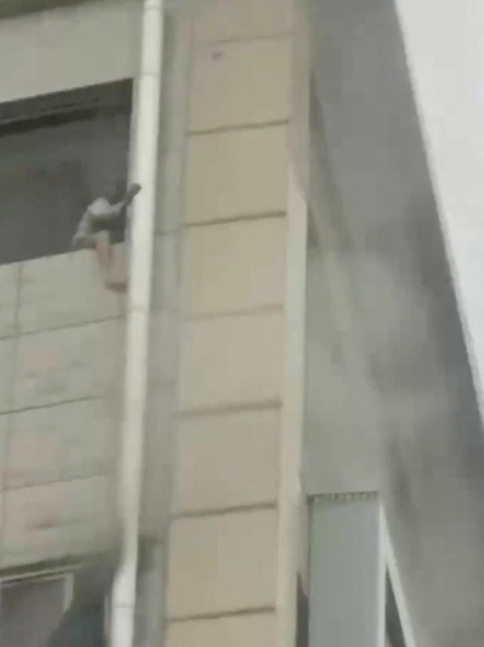 A person tries to climb outside a window during a deadly fire at a shopping centre, in the city of Zigong, Sichuan, China, July 17, 2024 in this screengrab taken from a social media video. Video Obtained By Reuters/via REUTERS  THIS IMAGE HAS BEEN SUPPLIED BY A THIRD PARTY. NO RESALES. NO ARCHIVES.