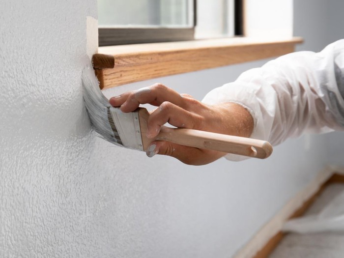 Man painting interior of home in gray paint