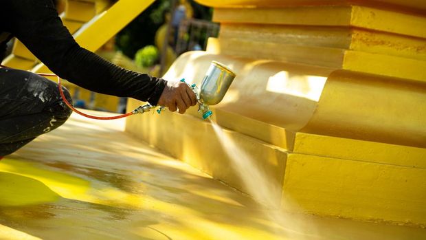 Artist paints gold in a temple area in Thailand,  Gold is an auspicious color for Buddhists.