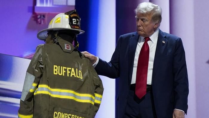 Aksi Trump Beri Penghormatan Pada Damkar yang Tewas di Kampanye Pilpres Republican presidential nominee and former U.S. President Donald Trump touches the turnout coat and helmet of former Buffalo Township Volunteer Fire Department chief Corey Comperatore, who was killed at his rally last week, as he gives his acceptance speech on Day 4 of the Republican National Convention (RNC), at the Fiserv Forum in Milwaukee, Wisconsin, U.S., July 18, 2024. REUTERS/Elizabeth Frantz