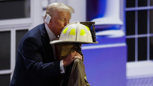 Republican presidential nominee and former U.S. President Donald Trump kisses the turnout coat and helmet of former Buffalo Township Volunteer Fire Department chief Corey Comperatore, who was killed at his rally last week, as he gives his acceptance speech on Day 4 of the Republican National Convention (RNC), at the Fiserv Forum in Milwaukee, Wisconsin, U.S., July 18, 2024. REUTERS/Marco Bello