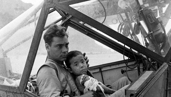 Seorang Tentara Amerika Memangku Seorang Anak Laki-Laki Jepang Yang Terluka Dan Melindunginya Dari Hujan Di Kokpit Pesawat Selama Pertempuran Saipan Sambil Menunggu Untuk Mengangkut Anak Muda Itu Ke Rumah Sakit. Juli, 1944 Foto: via Boredpanda