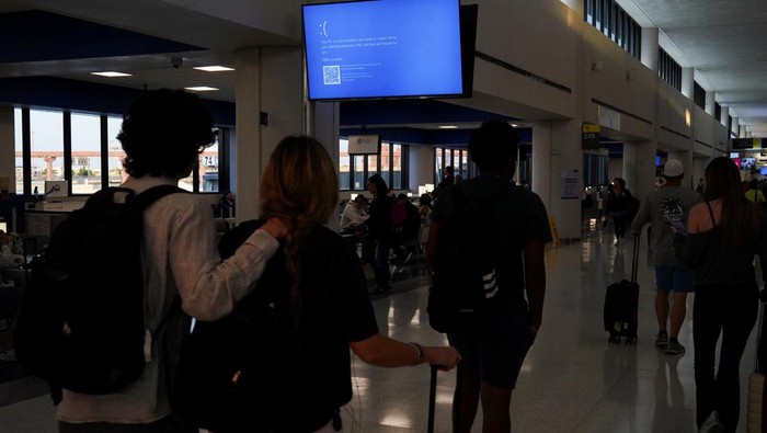 An item of checked luggage is seen near a monitor displaying a blue error screen, also known as the ?Blue Screen of Death? at a baggage claim area inside Terminal C in Newark International Airport, after United Airlines and other airlines grounded flights due to a worldwide tech outage caused by an update to Crowdstrike's 