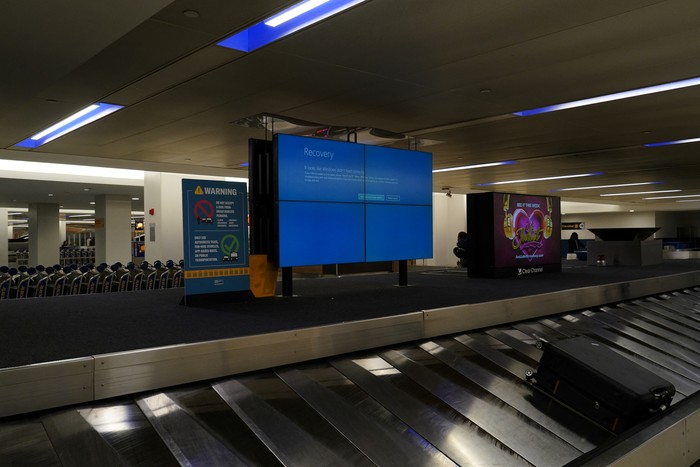 An item of checked luggage is seen near a monitor displaying a blue error screen, also known as the ?Blue Screen of Death? at a baggage claim area inside Terminal C in Newark International Airport, after United Airlines and other airlines grounded flights due to a worldwide tech outage caused by an update to Crowdstrikes 