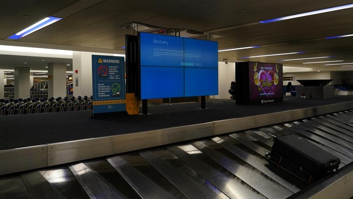 An item of checked luggage is seen near a monitor displaying a blue error screen, also known as the ?Blue Screen of Death? at a baggage claim area inside Terminal C in Newark International Airport, after United Airlines and other airlines grounded flights due to a worldwide tech outage caused by an update to Crowdstrikes 