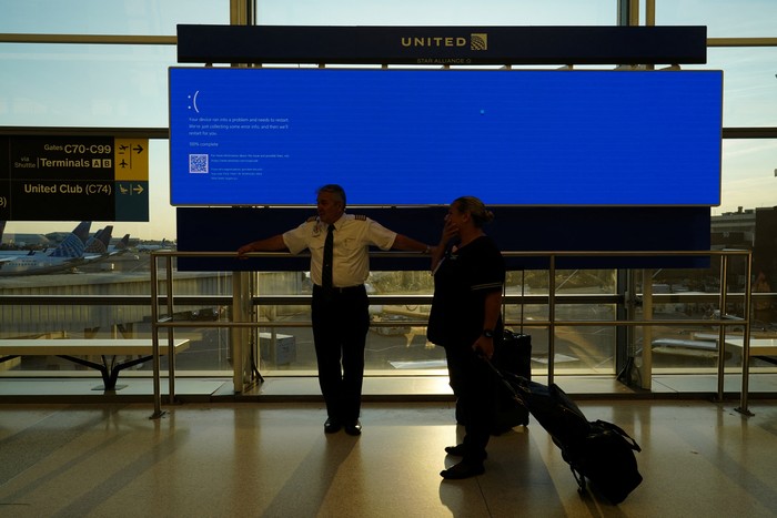 An item of checked luggage is seen near a monitor displaying a blue error screen, also known as the ?Blue Screen of Death? at a baggage claim area inside Terminal C in Newark International Airport, after United Airlines and other airlines grounded flights due to a worldwide tech outage caused by an update to Crowdstrikes 