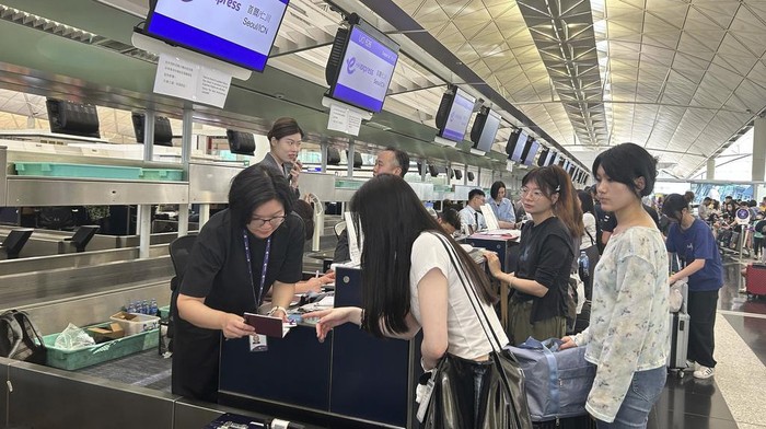 Passengers line up for manual check-in at the Hong Kong International Airport in Hong Kong, Friday, July 19, 2024. An internet outage affecting Microsoft is disrupting flights, banks, media outlets and companies across the world. (AP Photo/Kanis Leung)