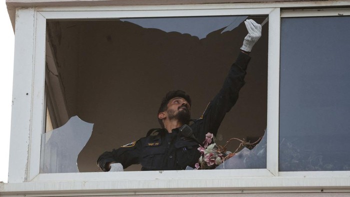 An investigator inspects a damaged window of a building at the site of an explosion, amid the Israel-Hamas conflict in Tel Aviv, Israel July 19, 2024. REUTERS/Ricardo Moraes     TPX IMAGES OF THE DAY
