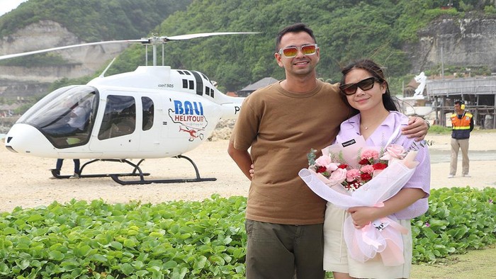 Raffi Ahmad dan Nagita Slavina berfoto dengan latar belakang helikopter Bali Helitour. (Dok. Bali Helitour)