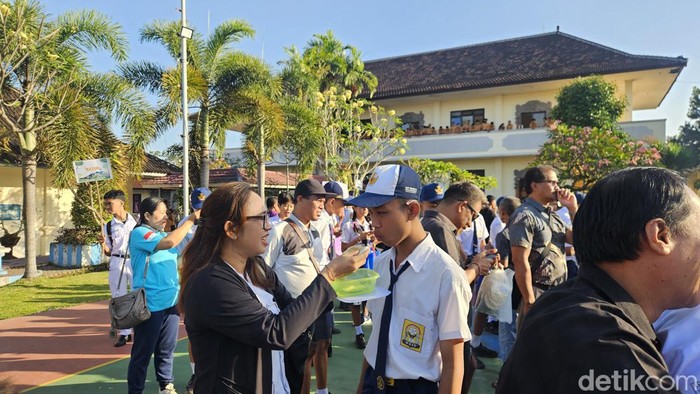 Keharuan siswa baru dan orang tua mereka saat dilepas dengan menyuapi makan di lapangan sekolah SMAN 2 Semarapura, Klungkung, Jumat (18/7/2024).