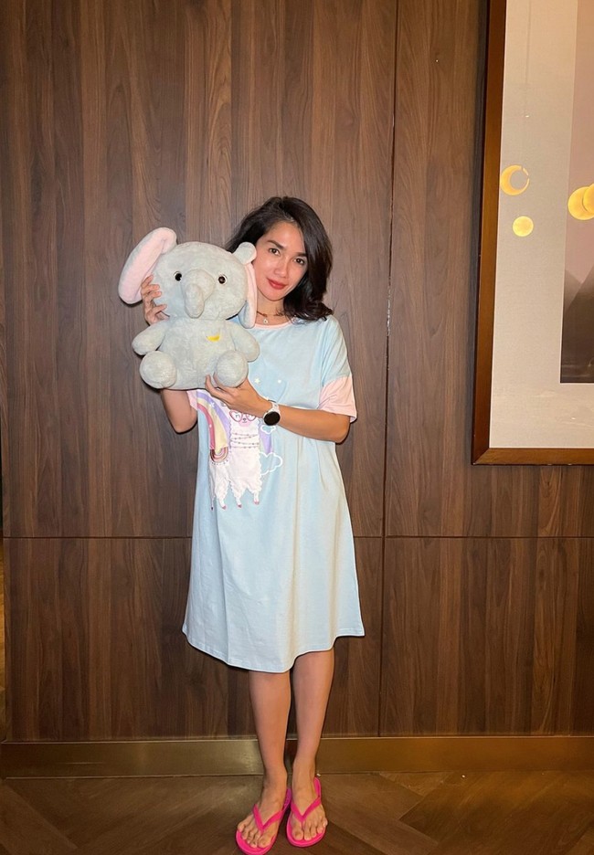 Ussy tampil cantik mengenakan daster berwarna biru dan merah muda. Penampilannya itu dilengkapi dengan sandal jepit berwarna fuschia. Foto: Instagram/@ussypratama