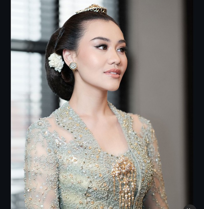 Penampilan Aaliyah semakin memukau dengan riasan wajah natural yang tetap memberi kesan glamor, terutama pada bagian mata. Rambutnya ditata dengan sanggul ukel tekuk, dihiasi gunungan sariayu di bagian atas serta sepasang bunga putih di belakang telinga, menambah kesan anggun dan klasik. Foto: Dok. Instagram, Youtube Thariq Halilintar