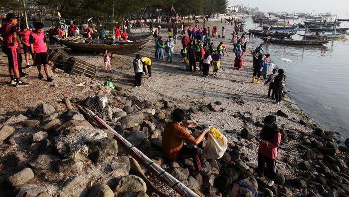 Seorang pelajar memungut sampah di Pantai Kenjeran, Surabaya, Jawa Timur, Minggu (21/7/2024). Aksi bersih-bersih pantai yang dilakukan sejumlah pelajar didampingi orang tuanya dan komunitas Tunas Hijau itu merupakan wujud kepedulian terhadap kebersihan lingkungan khususnya di lokasi wisata kawasan pesisir. ANTARA FOTO/Didik Suhartono/wpa.