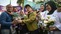 Muhaimin Iskandar didampingi istrinya Rustini Murtadho membagikan bunga kepada warga saat mensosialisasikan UU KIA di CFD Jakarta, Minggu (21/7/2024).
