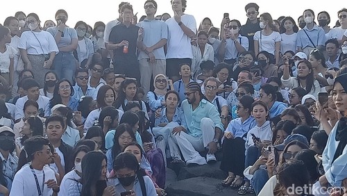 Jennifer Coppen bersama keluarga dan fans duduk di Pantai Lembeng, Desa Lembeng, Kecamatan Sukawati, Gianyar, saat prosesi pelarungan abu Yitta Dali Wassink, Minggu (21/7/2024). (Ni Made Lastri Karsiani Putri/detikBali)