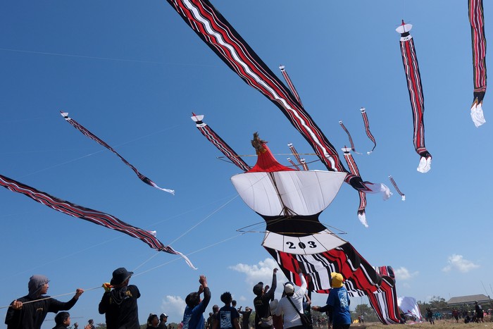 Sejumlah peserta berusaha menangkap layang-layang tradisional Bali yang diturunkan saat mengikuti perlombaan pada Festival Layangan Piala Gubernur Bali 2024 di Pantai Padanggalak, Denpasar, Bali, Minggu (21/7/2024). Kegiatan yang diselenggarakan oleh Komunitas Seni Layanan Bali bekerja sama dengan Pemerintah Provinsi Bali tersebut diikuti 1.340 peserta  untuk pelestarian permainan tradisional Bali. ANTARA FOTO/Nyoman Hendra Wibowo/wpa.