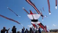 Sejumlah peserta berusaha menangkap layang-layang tradisional Bali yang diturunkan saat mengikuti perlombaan pada Festival Layangan Piala Gubernur Bali 2024 di Pantai Padanggalak, Denpasar, Bali, Minggu (21/7/2024).