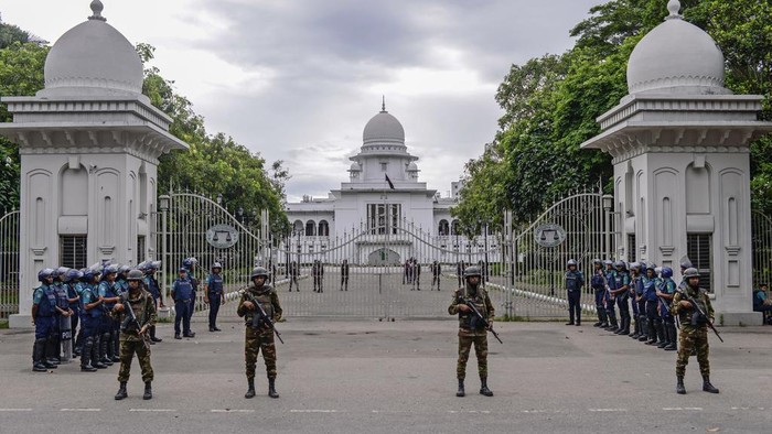 Police stand behind a barricade during an imposed curfew after scores were killed and hundreds injured in clashes over the allocation of civil service jobs, in Dhaka, Bangladesh, Sunday, July 21, 2024. (AP Photo/Mahmud Hossain Opu)