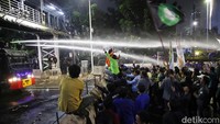 Polisi menyemprotkan air untuk membubarkan massa.  