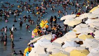 Meski sedang dihantam gelombang panas, para wisatawan tetap berlibur ke pantai.