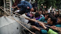 Pantauan detikcom di lokasi, Senin (22/7/2024), massa aksi mulai mengaitkan tali tambang ke barikade beton sisi timur. Percobaan pertama gagal lantaran barier beton tidak jatuh ketika ditarik beberapa orang.