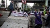 Kemudian percobaan kedua sekitar pukul 17.30 WIB, massa bergeser mengaitkan tali tambang di sisi barat yang terpasang di atas trotoar. Hanya membutuhkan waktu beberapa menit, satu barikade beton tumbang.