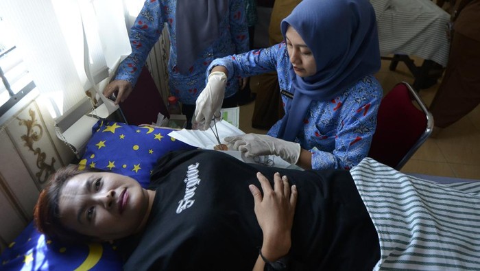 Petugas kesehatan memasang alat kontrasepsi jenis implan kepada warga akseptor KB di Puskesmas Hanura, Kecamatan Teluk Pandan, Kabupaten Pesawaran, Lampung, Senin (22/7/2024). Pelayanan KB gratis bagi masyarakat tersebut merupakan rangkaian kegiatan peringatan HUT ke-17 Kabupaten Pesawaran. ANTARA FOTO/Ardiansyah/nym.