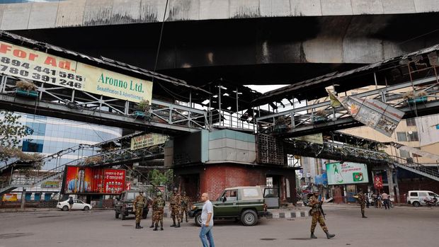 Tentara berjaga di bawah jembatan penyeberangan yang dibakar oleh massa dalam bentrokan setelah kekerasan meletus menyusul protes mahasiswa terhadap kuota pekerjaan pemerintah, di Dhaka, Bangladesh, 22 Juli 2024. (REUTERS/Mohammad Ponir Hossain)